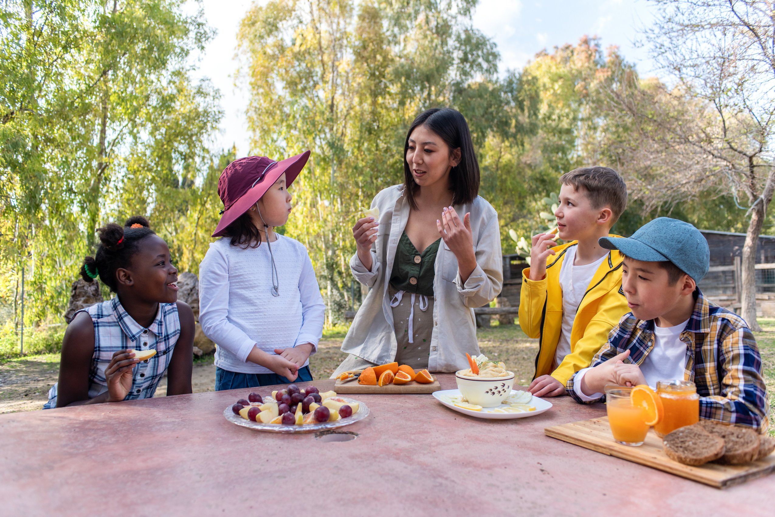 Woman and Diverse Kids Eating Together Outdoors